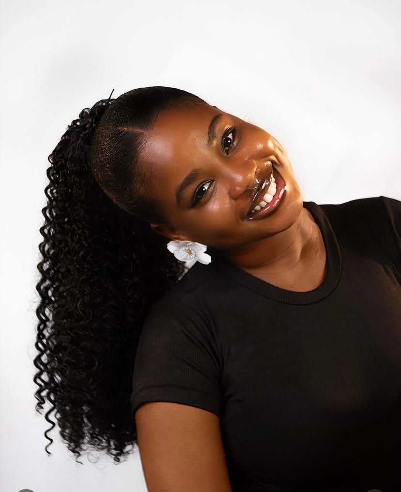 A Glowsbeauty client smiling, wearing a long curly ponytail